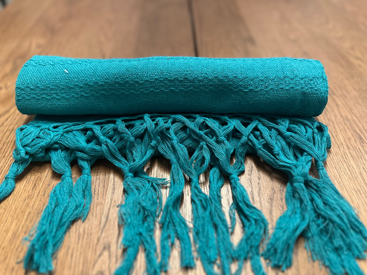 Jade Maya teal Mexican rebozo baby wrap rolled with teal hand-knotted fringe in front | Lola My Love