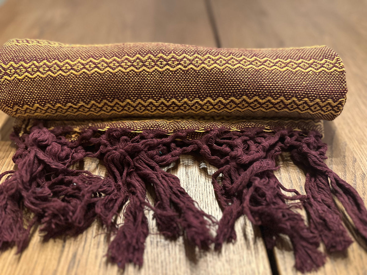 Mole Dorado burgundy and gold Mexican rebozo baby wrap rolled with burgundy hand-knotted fringe in front | Lola My Love