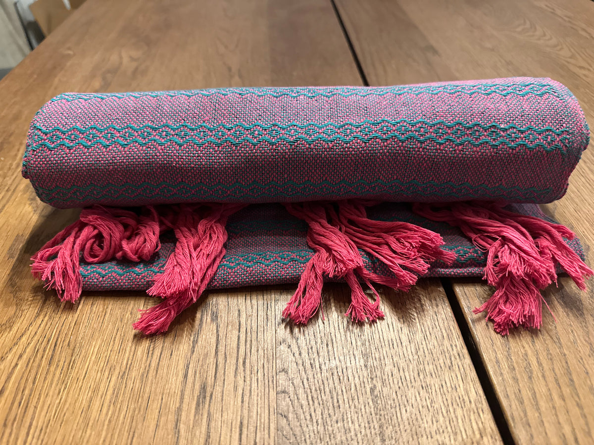 Tuna Rosa pink and teal Mexican rebozo baby wrap rolled with pink hand-knotted fringe in front | Lola My Love